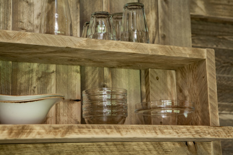 Estantes de madera con vasos y cuencos en una tienda safari en Forest Lodge Junior de Sandberghe, Países Bajos.