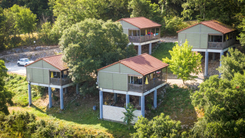 Cuatro cabañas elevadas con techos rojos rodeadas de árboles en Chalet Belvedere, La Draille, Francia.