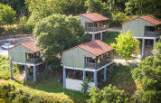 Cuatro cabañas elevadas con techos rojos rodeadas de árboles en Chalet Belvedere, La Draille, Francia.