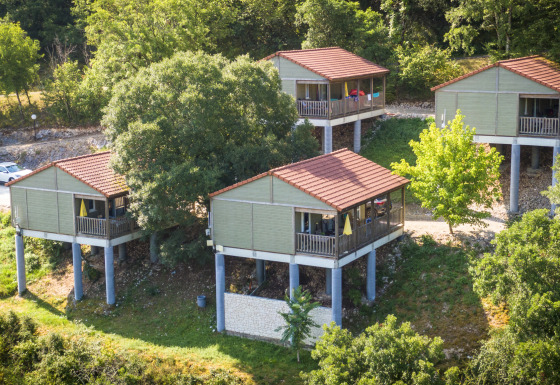 Cuatro cabañas elevadas con techos rojos rodeadas de árboles en Chalet Belvedere, La Draille, Francia.
