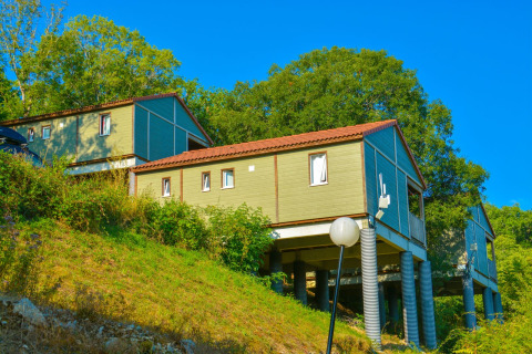 Cabañas elevadas en Chalet Belvedere, La Draille, Francia, rodeadas de árboles y vegetación en una colina.