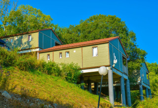 Cabañas elevadas en Chalet Belvedere, La Draille, Francia, rodeadas de árboles y vegetación en una colina.