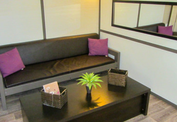 Area lounge di un lodge con divano marrone, cuscini viola, tavolino nero, pianta e specchio a muro.