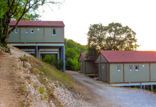 Cabañas con techos rojos sobre pilotes en Chalet Belvedere, La Draille, Francia, rodeadas de bosque y colinas.