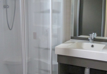 Bagno moderno in un lodge con box doccia in vetro, lavandino bianco e ampio specchio sopra il lavabo.