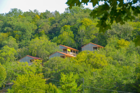 Chalets de Chalet Belvedere en La Draille, Francia, situados en una colina verde rodeada de árboles frondosos.