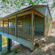 Accogliente lodge in legno su palafitte con veranda coperta, immerso tra alberi e natura tranquilla.