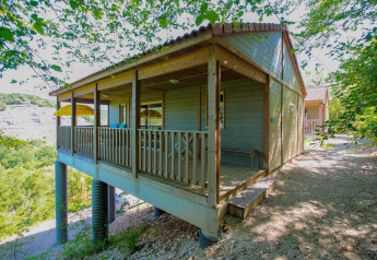 Accogliente lodge in legno su palafitte con veranda coperta, immerso tra alberi e natura tranquilla.