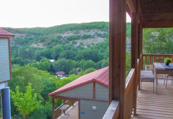 Zicht vanaf het terras van Chalet Belvedere in La Draille, Frankrijk, op groene heuvels en chalets.