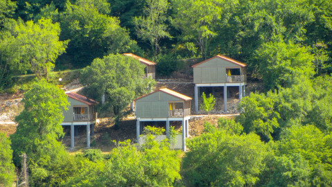 Cuatro cabañas de madera elevadas con techos rojos en Chalet Belvedere, La Draille, rodeadas de bosque en Francia.