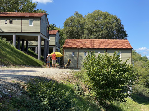 Dos personas están de pie junto a un chalet con techo rojo y sombrilla amarilla en Chalet Belvedere, La Draille, Francia.