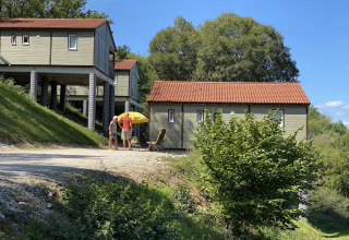 Dos personas están de pie junto a un chalet con techo rojo y sombrilla amarilla en Chalet Belvedere, La Draille, Francia.