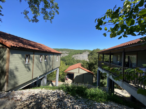 El lodge Chalet Belvedere en La Draille, Francia, con vistas a colinas verdes y un cielo azul claro.