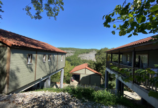 El lodge Chalet Belvedere en La Draille, Francia, con vistas a colinas verdes y un cielo azul claro.