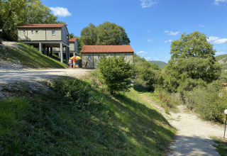 Chalet Belvedere en La Draille, Francia, rodeado de colinas verdes, árboles y un cielo azul brillante.