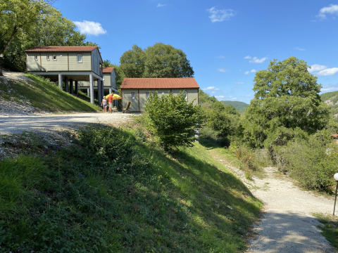 Chalet Belvedere en La Draille, Francia, rodeado de colinas verdes, árboles y un cielo azul brillante.