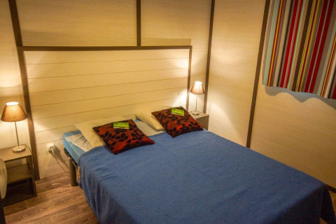 Dormitorio en Chalet Belvedere Deluxe en La Draille, Francia con cama doble, lámparas y cortina colorida.