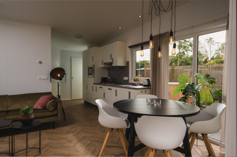 Soggiorno e cucina moderni nella Panorama lodge + wellness a Vakantiepark Hölte, con grandi finestre.