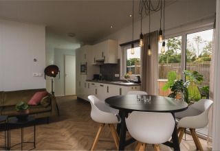 Moderne stue og køkken i Panorama lodge + wellness på Vakantiepark Hölte, med spisebord og store vinduer.