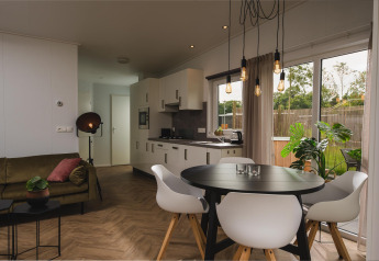 Moderne stue og køkken i Panorama lodge + wellness på Vakantiepark Hölte, med spisebord og store vinduer.