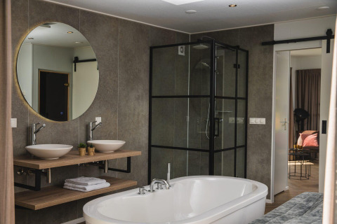 Bagno moderno in una tiny house con vasca indipendente, doppio lavabo e cabina doccia in vetro.