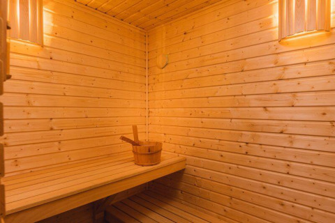 Interieur van een tiny house sauna met houten wanden, een bankje en warme sfeerverlichting.