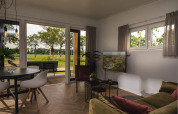 Moderne woonkamer in de Panorama Lodge met grote ramen, uitzicht op het groene landschap en luxe inrichting.