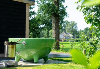 Bañera verde al aire libre y wellness junto a cabaña en Panorama Lodge, Vakantiepark Hölte, Países Bajos.