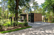 Cabaña moderna Veluwe hoeve en Resort Veluwe, Países Bajos, rodeada de vegetación y árboles verdes.