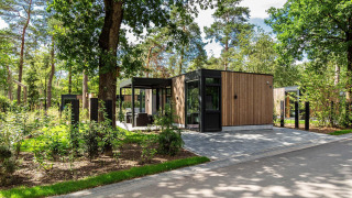 Moderno lodge Veluwe hoeve al Resort Veluwe nei Paesi Bassi, immerso nel verde e alberi rigogliosi.