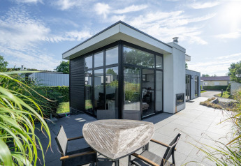 Moderne Cube Exclusif 4 lodge op Schoneveld in Nederland met grote ramen, zonneterras en tuin.
