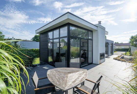 Moderne Cube Exclusif 4 lodge op Schoneveld in Nederland met grote ramen, zonneterras en tuin.