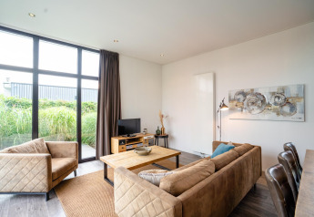 Bright living room in Cube Exclusif 4 lodge at Schoneveld, Netherlands, with large windows and cozy seating.