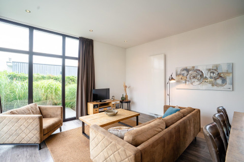 Lichte leefruimte in Cube Exclusif 4 lodge te Schoneveld, Nederland, met grote ramen en cosy zitplaatsen.