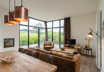 Moderne woonkamer in Cube Exclusif 4 lodge te Schoneveld, Nederland, met grote ramen en sfeervol interieur.