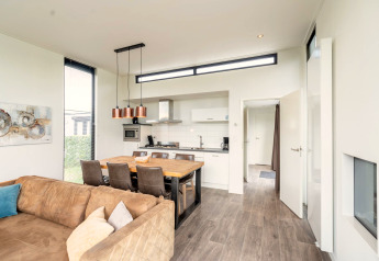 Lyst og moderne køkken og spiseområde i Cube Exclusif 4 lodge ved Schoneveld, Holland, med sofa.