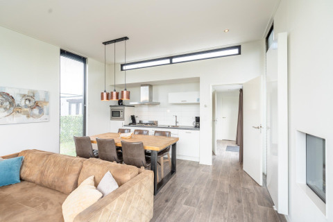 Cuisine et salle à manger moderne et lumineuse au lodge Cube Exclusif 4 à Schoneveld, Pays-Bas, avec canapé.