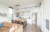 Bright modern kitchen and dining area in Cube Exclusif 4 lodge at Schoneveld, Netherlands, with sofa.