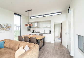 Bright modern kitchen and dining area in Cube Exclusif 4 lodge at Schoneveld, Netherlands, with sofa.