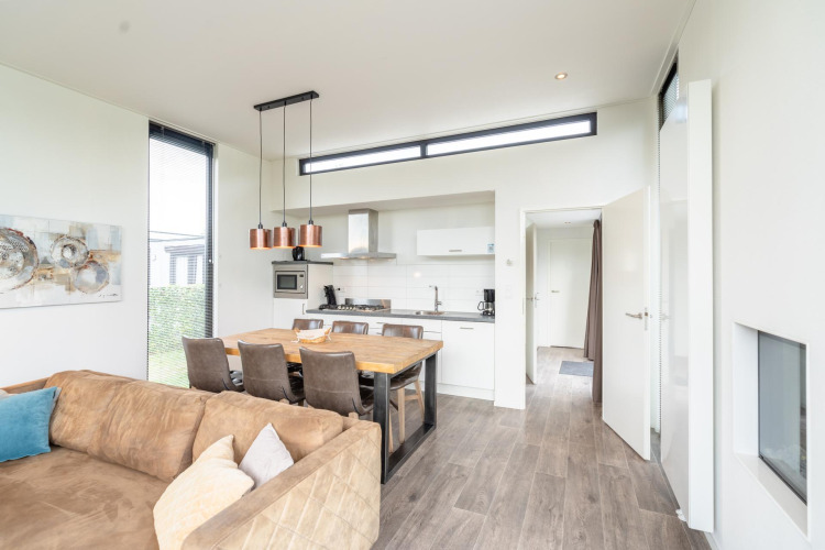 Cocina y comedor modernos y luminosos en la lodge Cube Exclusif 4 en Schoneveld, Países Bajos, con sofá.