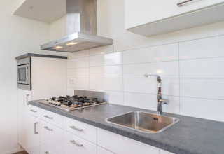 Cocina moderna en Cube Exclusif 4 con estufa a gas, extractor y fregadero en Schoneveld, Países Bajos.