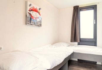 Bright bedroom in Cube Exclusif 4 at Schoneveld, Netherlands with two beds, a window, and modern wall art.