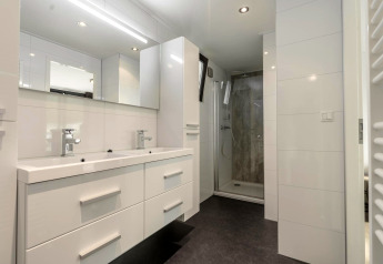 Modern bathroom with double sink, mirror, cabinets and walk-in shower in Cube Exclusif 4 at Schoneveld.