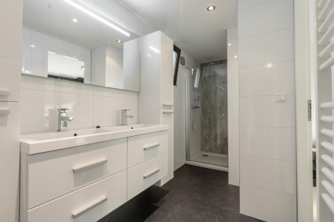Salle de bains moderne avec double vasque, miroir, rangements et douche au Cube Exclusif 4 à Schoneveld.