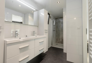 Modern bathroom with double sink, mirror, cabinets and walk-in shower in Cube Exclusif 4 at Schoneveld.