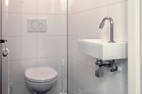 Modernes weißes Badezimmer mit wandhängender Toilette und kleinem Waschbecken im Cube Exclusif 4, Schoneveld.