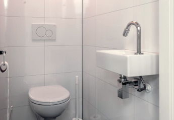 Moderne hvidt badeværelse med væghængt toilet og lille firkantet håndvask på Cube Exclusif 4, Schoneveld.