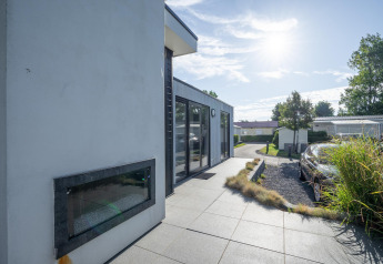 Außenaufnahme der Lodge Cube Exclusif 4 in Schoneveld, Niederlande, mit moderner Terrasse und Sonnenschein.