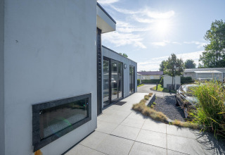 Außenaufnahme der Lodge Cube Exclusif 4 in Schoneveld, Niederlande, mit moderner Terrasse und Sonnenschein.