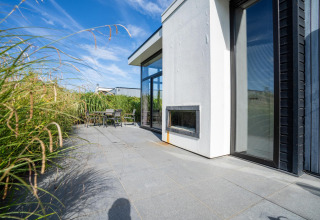 Terrasse extérieure du Cube Exclusif 4 à Schoneveld, Pays-Bas, avec herbe haute et architecture moderne.